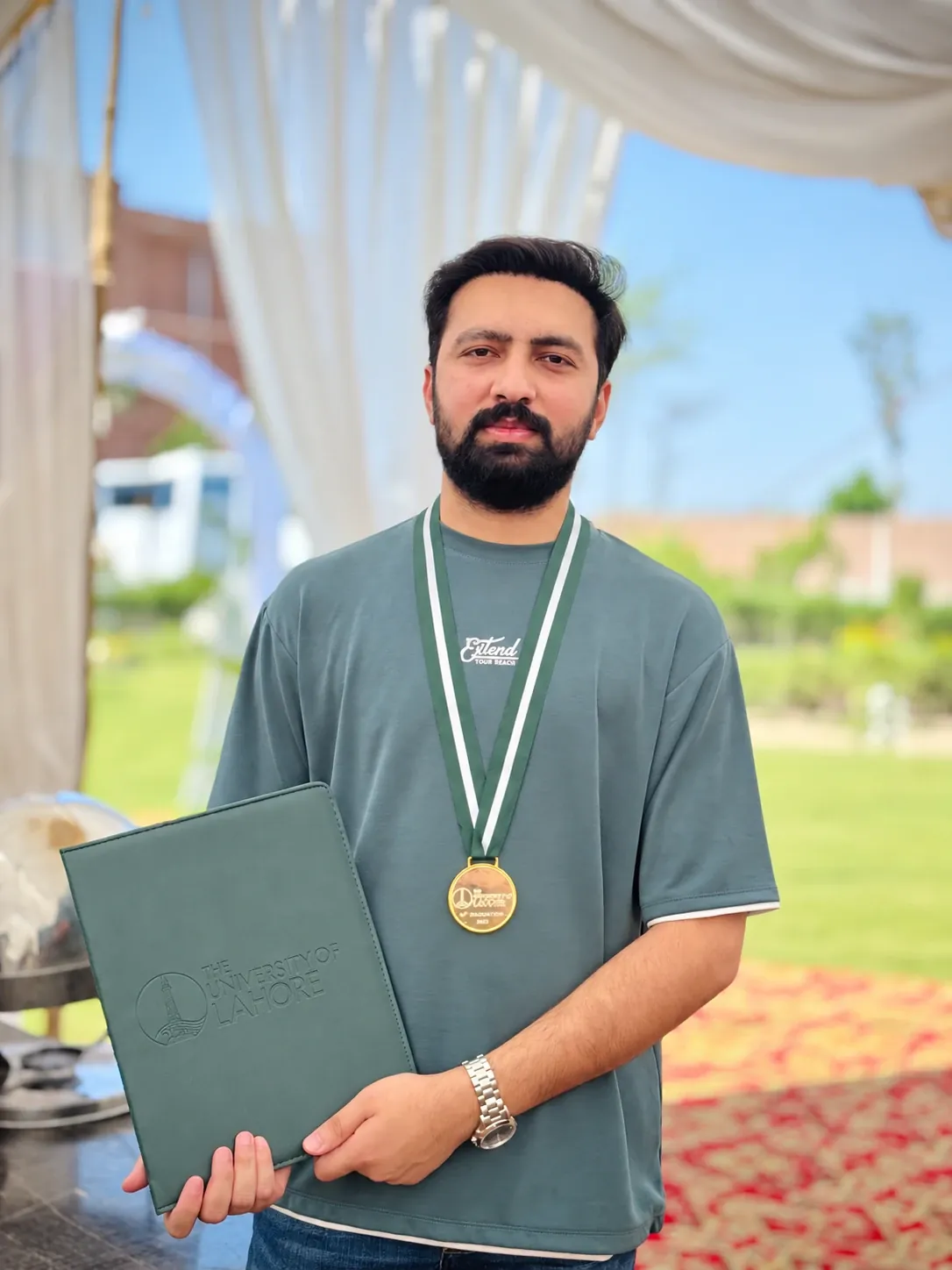 Usama Tanveer wearing his gold medal and holding his University of Lahore degree folder